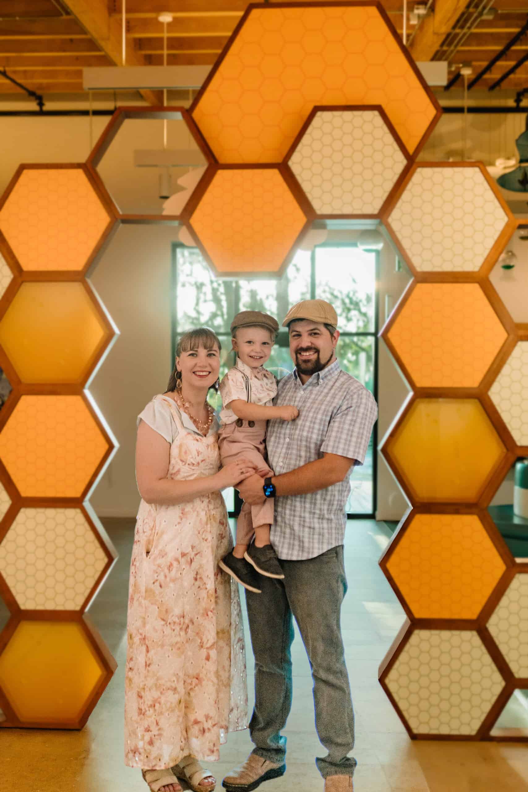 Robert, Alyssa, and Max standing in front of the honeycomb wall at Honey’s BBQ