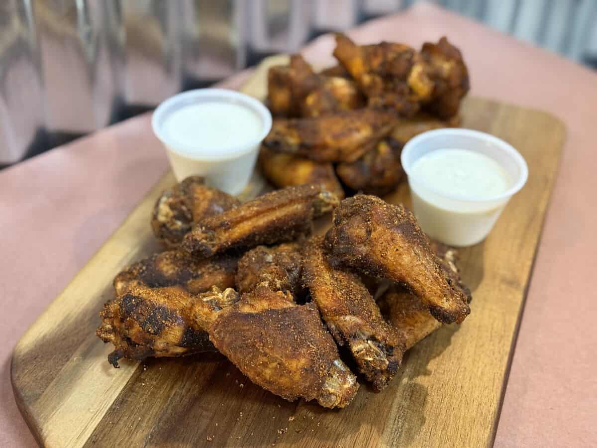 Smoked chicken wings served with two cups of housemade ranch on a wooden board